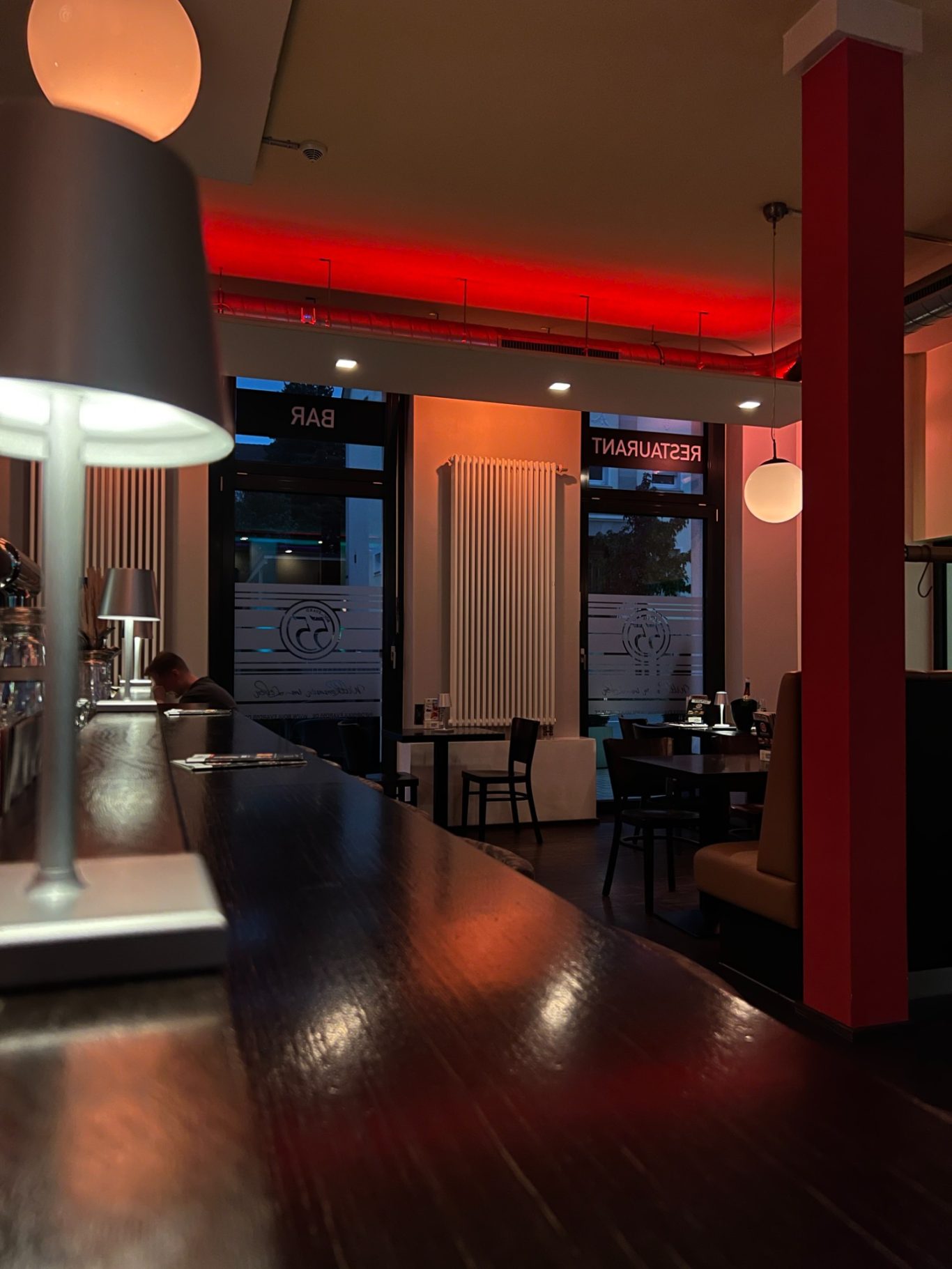 Dunkel beleuchteter Innenraum eines modernen Restaurants mit roten Akzenten.